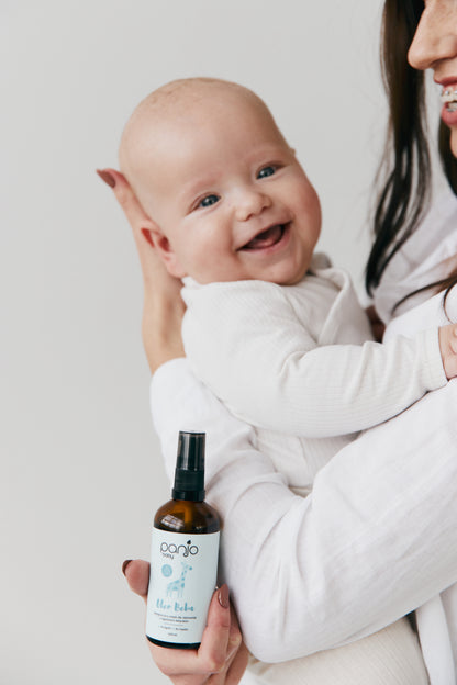 Mama z niemowlakiem, trzymająca naturalny olejek dla niewoląt. Szczęśliwy maluch.