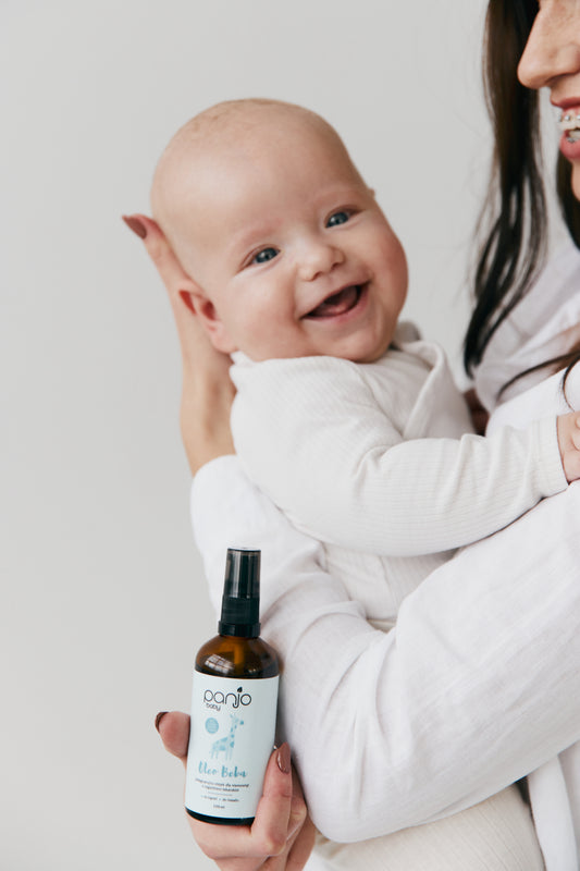 Mama z niemowlakiem, trzymająca naturalny olejek dla niewoląt. Szczęśliwy maluch.